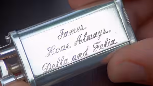 Hand holding silver case engraved James Love Always Della and Felix