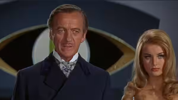 Man with mustache in dark coat standing beside blonde woman