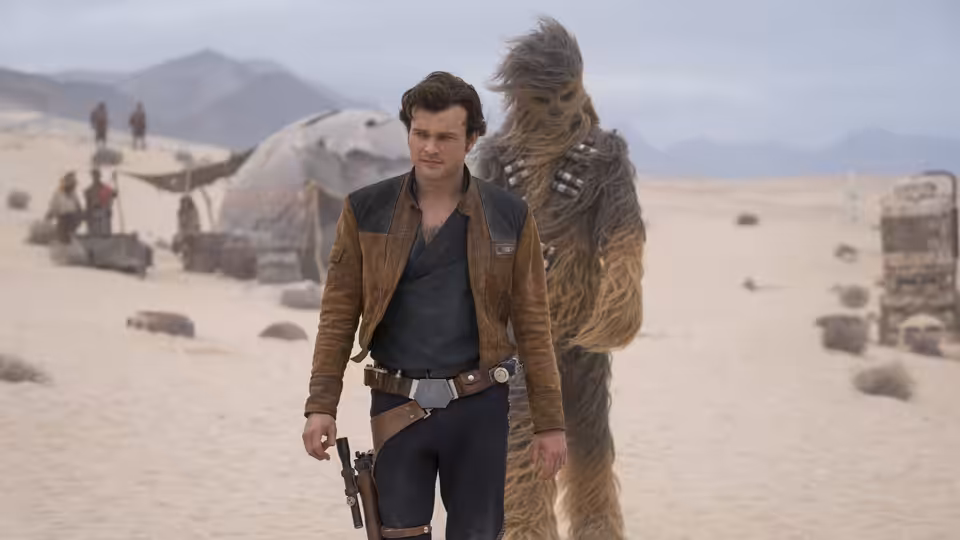 Han Solo (Alden Ehrenreich) and Chewbacca walking through a desert settlement