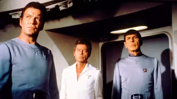 Kirk, McCoy and Spock standing together in a starship corridor