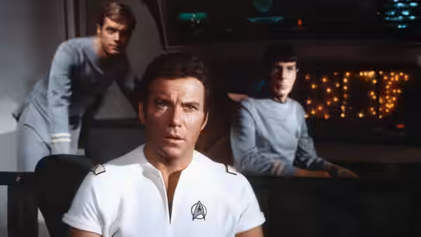 Admiral James T. Kirk seated on the bridge with Spock and another officer