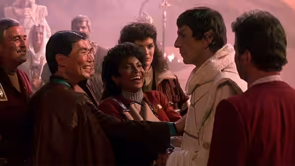 Starfleet officers gathered closely in a hazy reddish interior