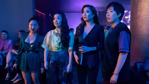 Four women standing in a purple-lit club looking surprised