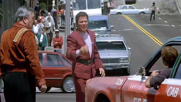 Admiral James T. Kirk (William Shatner) gestures beside a taxi on a busy street