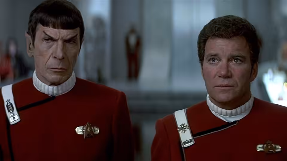 Spock (Leonard Nimoy) stands beside a fellow officer in red Starfleet uniforms