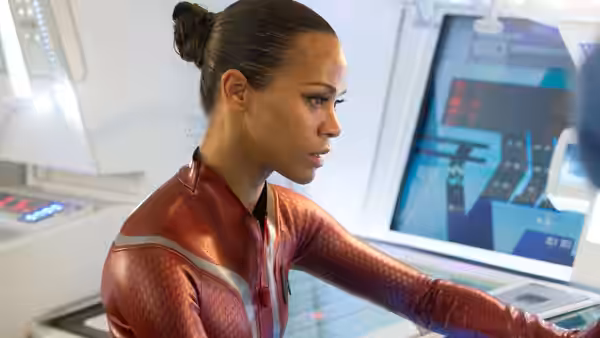 Uhura (Zoe Saldaña) in a red uniform works at a control console