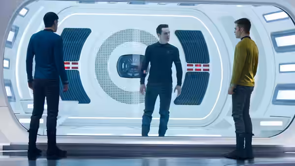 Spock (Zachary Quinto) stands with two officers in a white corridor