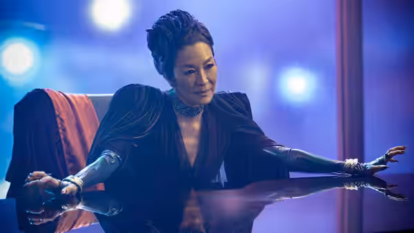 Philippa Georgiou (Michelle Yeoh) with cybernetic arms leaning on a reflective table
