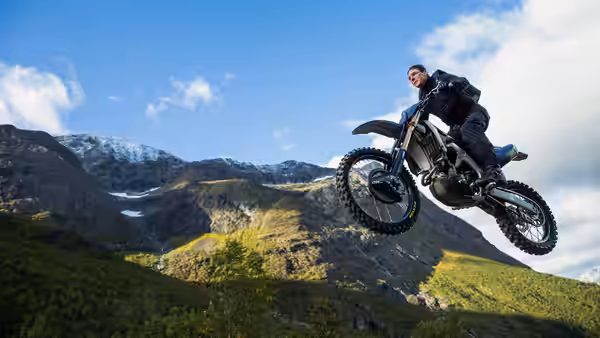 Ethan Hunt (Tom Cruise) airborne on a dirt bike over mountains