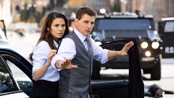 Ethan Hunt (Tom Cruise) gesturing beside a woman by an open car door