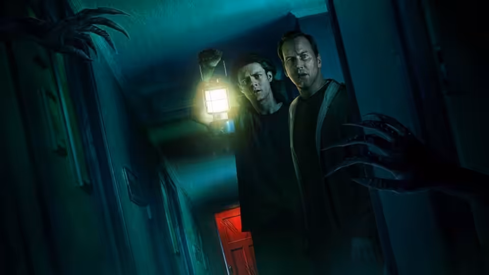 Two young men stand in a shadowy hallway as clawed hands reach out
