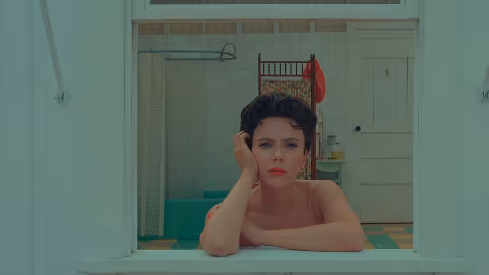 Midge Campbell (Scarlett Johansson) leaning on a windowsill in a bathroom