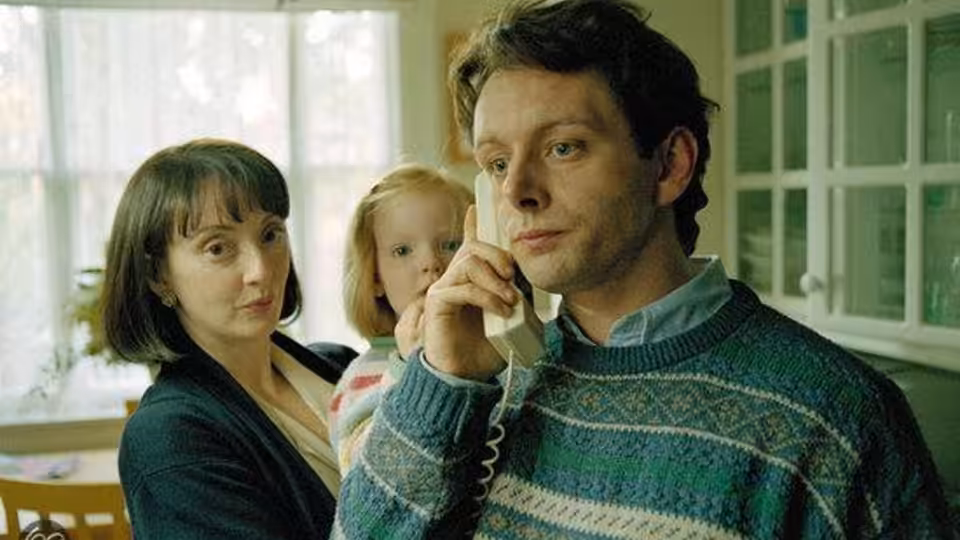 Gordon Brown (David Morrissey) talks on a telephone beside a woman and child
