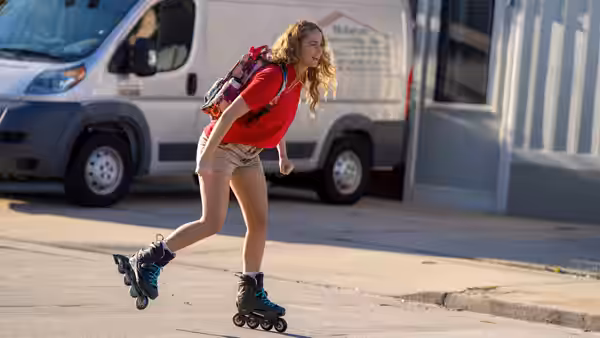 Maddie Barker (Jennifer Lawrence) rollerblading on a street beside a white van