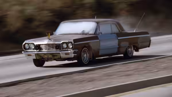 A customized blue-and-white sedan speeds along a wooded road