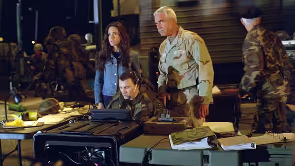 Betty Ross and General Ross stand over military equipment at a field command post
