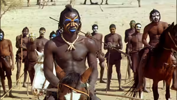 A painted warrior on horseback faces a line of armed men in open ground