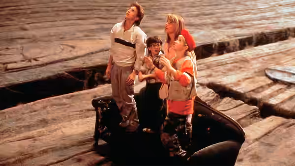 Four children stand on a shoe amid oversized wooden boards
