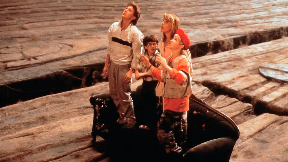 Four children stand on a shoe amid oversized wooden boards