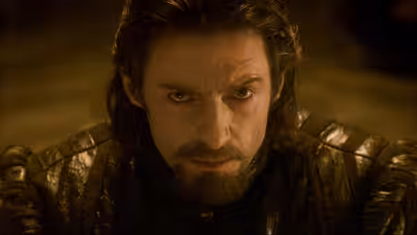 Tomás (Hugh Jackman) in dark armor stares ahead in a dimly lit chamber