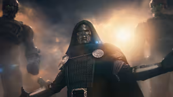 Doctor Doom (Robert Downey Jr.) stands in armor with his arms spread beneath a hood