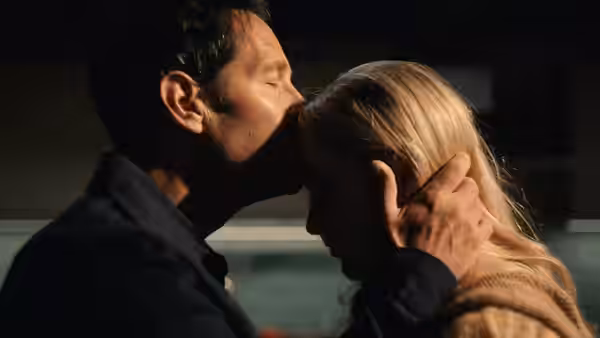 A man kisses a blonde woman’s forehead while holding her head gently