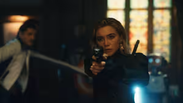 Sue Storm (Vanessa Kirby) aims a handgun inside a room as a man moves behind her