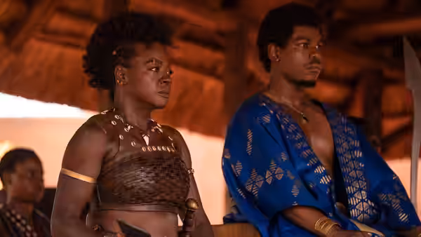 Nanisca (Viola Davis) stands beside King Ghezo (John Boyega) inside a wooden hall