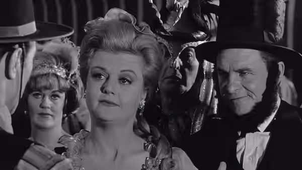 Mrs. Iselin (Angela Lansbury) stands among guests beside Senator Iselin (James Gregory)