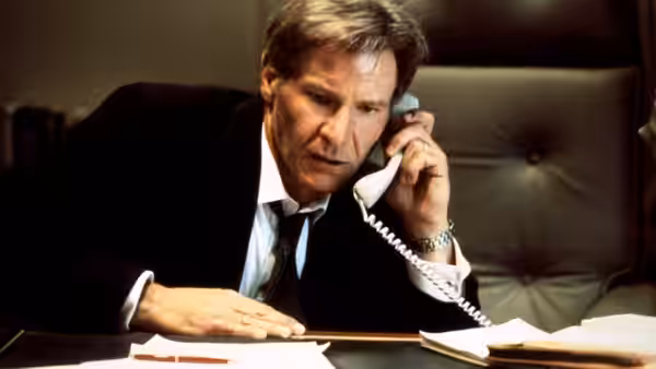 James Marshall (Harrison Ford) speaks on a corded telephone at his desk