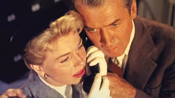 Jo McKenna (Doris Day) listens to Ben McKenna (James Stewart) whispering closely beside her