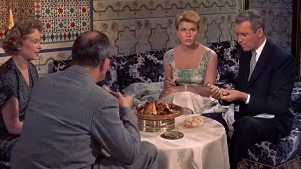 Jo McKenna (Doris Day) and Ben McKenna (James Stewart) sit at a restaurant table with other diners