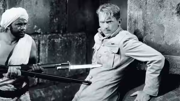 A turbaned Indian man holds a rifle beside a seated British soldier