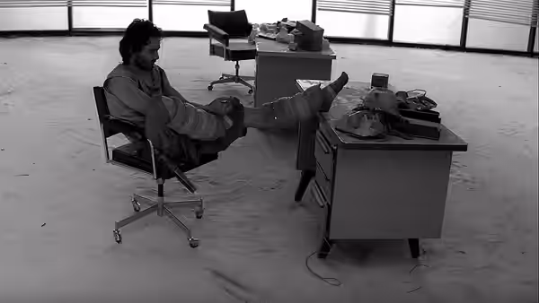 A man reclines with his feet on a desk in an empty office