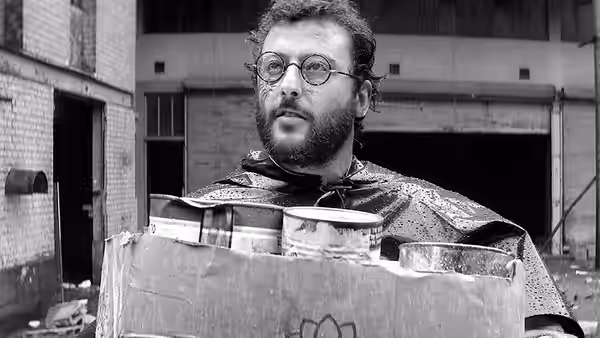 The Doctor (Jean Bouise) carries a crate of cans through an abandoned courtyard