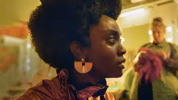 A woman with an afro hairstyle gazing sideways in a colorful room