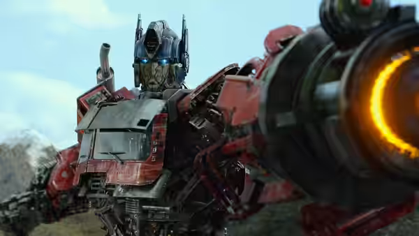 Optimus Prime aiming large glowing weapon across rocky landscape under cloudy sky