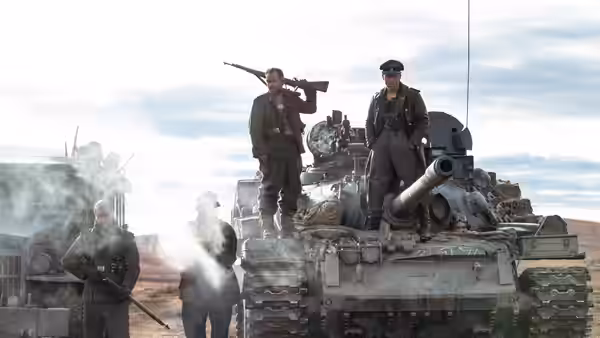 soldiers stand on and around a tank in an open field