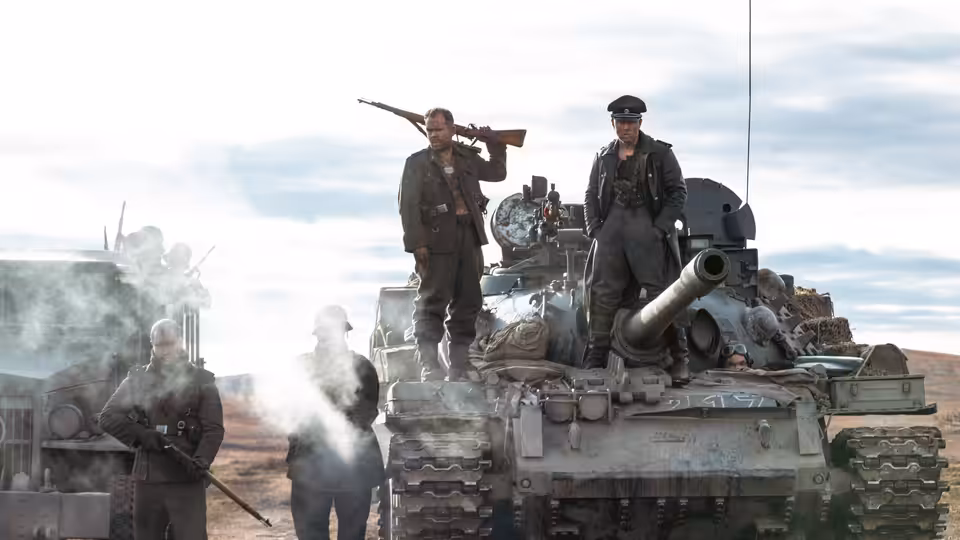 soldiers stand on and around a tank in an open field