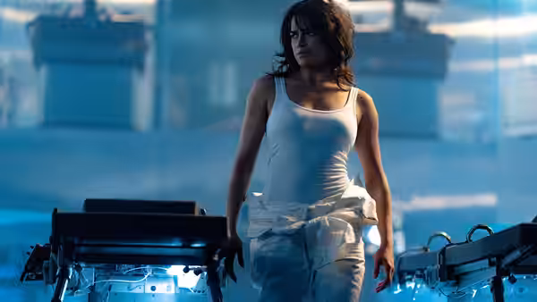 Letty (Michelle Rodriguez) walks through a blue-lit high-tech industrial facility
