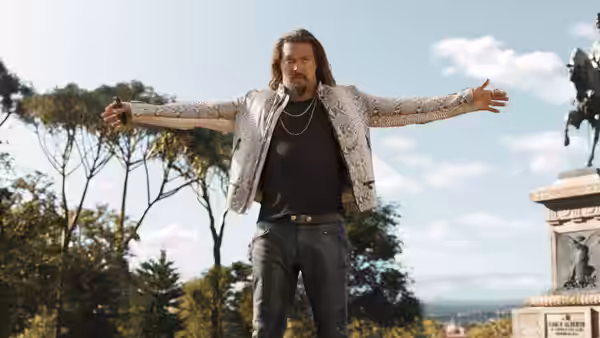 Dante (Jason Momoa) stands with arms outstretched before a large monument