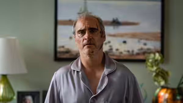 Beau Wassermann (Joaquin Phoenix) standing in a living room wearing pajamas