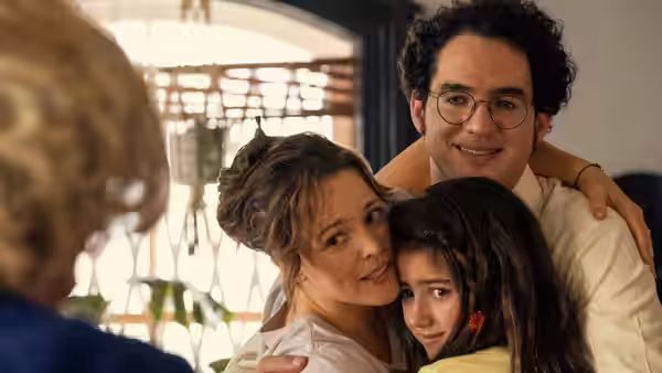 A couple and their daughter share a family hug indoors