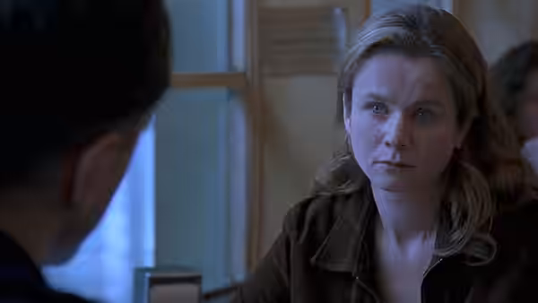 Maggie Hamill sits by a window, facing a man across the table