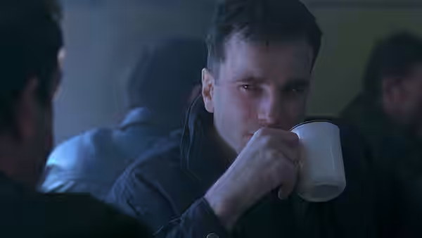 Danny Flynn drinks from a mug in a crowded room