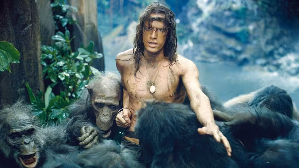 Tarzan (Christopher Lambert) gestures among apes gathered around him in the jungle
