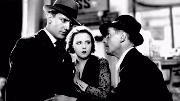 Alice White (Anny Ondra) stands between two men in hats inside a public room