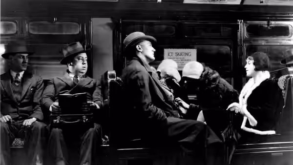 Passengers sit facing one another inside a subway carriage beneath an ice-skating advertisement