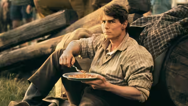 Joseph Donnelly (Tom Cruise) sits beside a wagon, eating from a plate