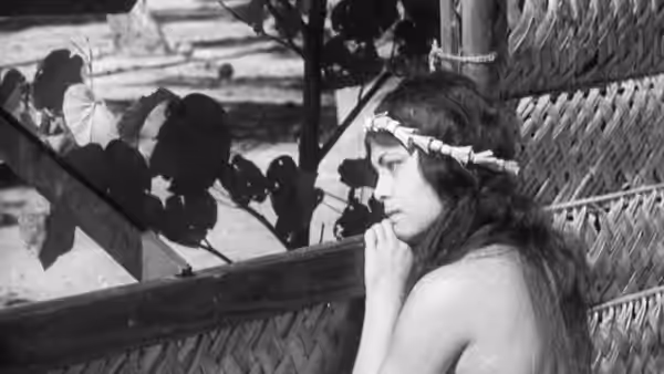 A young woman wearing a flower headband leans against a wooden railing
